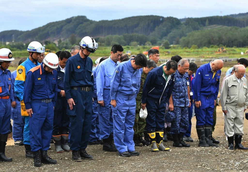 Il primo ministro giapponese Shinzo Abe (al centro) in raccoglimento per le vittime del terremoto di Atsuma (AFP)