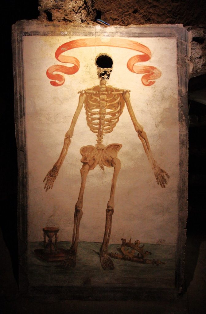 Nell’affresco all’inizio delle catacombe di San Gaudioso l’Allegoria della morte o «memento mori»; lo scheletro dipinto, con cranio vero spezzato in verticale, indica la clessidra, un libro, la corona e lo scettro come a suggerire il trionfo della morte sul tempo, sulla sapienza e sui poteri temporali dell’uomo. 