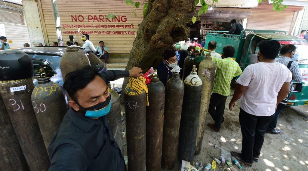 In fila per riempire le bombole di ossigeno per i parenti in ospedale a Delhi (Keystone)