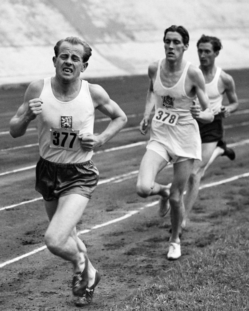 13 agosto 1948: durante la competizione internazionale di atletica leggera allo Stadio Olimpico di Londra, Emil Zatopek si trova in testa, con Erik Ahlden e Willem Slijkhuis dietro di lui (Noske, J.D. / Anefo)