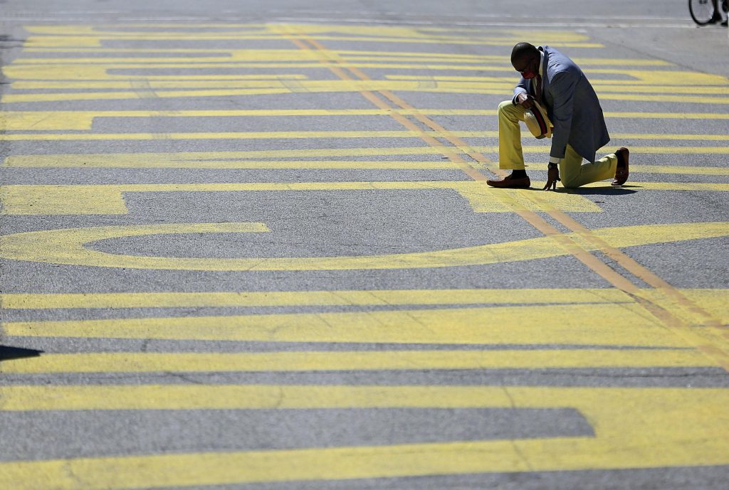 Un reverendo si inchina sulla scritta «Black Lives Matter» dipinta su una strada a Tulsa, Oklahoma (Keystone)