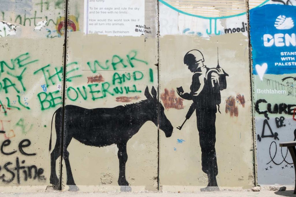 Il graffito di Banksy ritrae un soldato israeliano che chiede i documenti a un asino