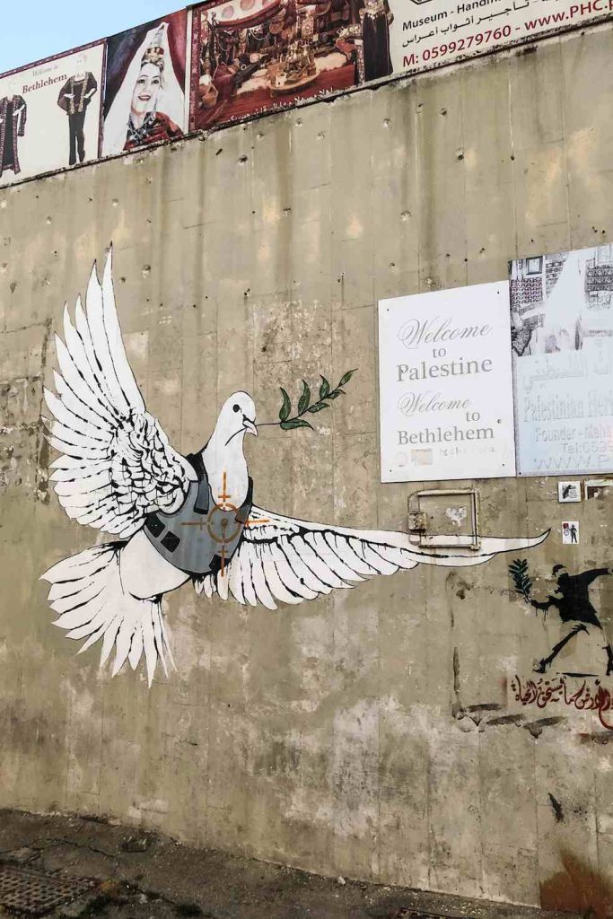 Graffito di Banksy: una colomba della pace con un giubbotto antiproiettile, bersaglio di un’arma da fuoco