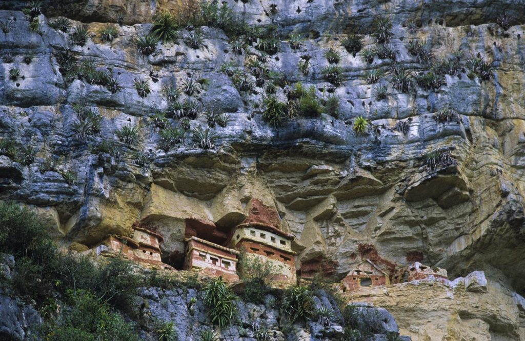 I colorati edifici funebri arroccati su una scogliera e dipinti con pittogrammi rossi