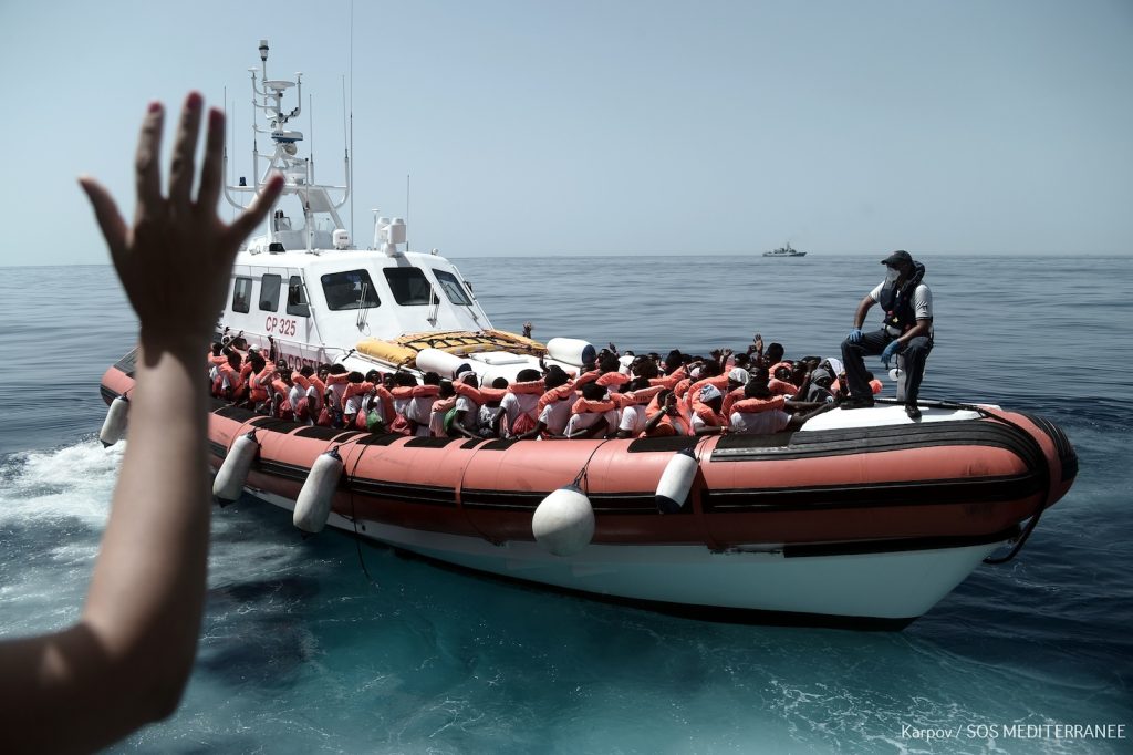 Alcuni migranti a bordo di una imbarcazione della Guardia Costiera e della Marina italiana prima di rimettersi in viaggio per Valencia (AFP)