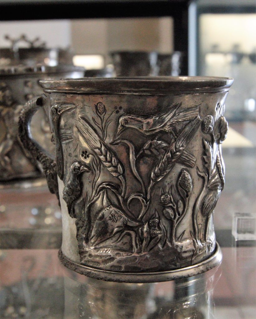 Dal MANN, una tazza cilindrica d’argento (I sec. d. C.) con scene di lotta tra cicogne e serpenti, rinvenuta nella Casa del Menandro