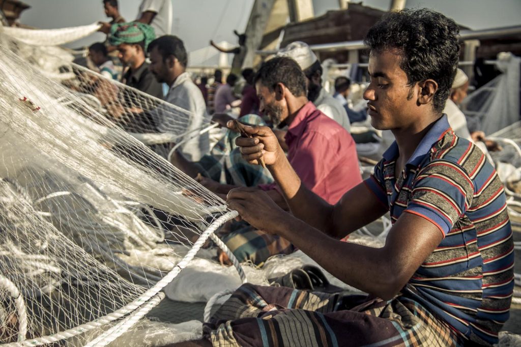 Operai giornalieri intrecciano le nuove reti da pesca