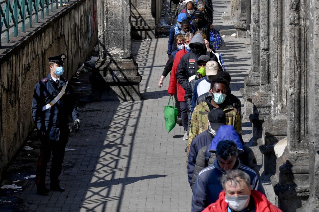 Milioni di famiglie affogano nei debiti e rischiano di cadere nel tranello dell’usura. In fila per un pasto a Napoli (Keystone)