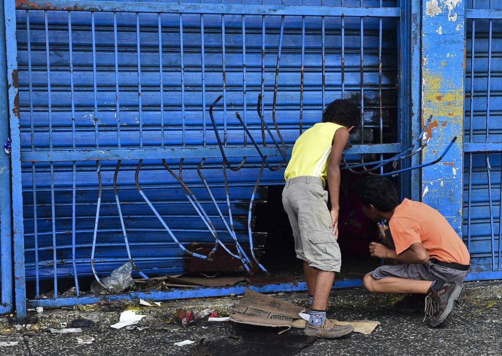 Ragazzi rovistano in un supermercato dopo una protesta contro il governo Maduro (AFP)