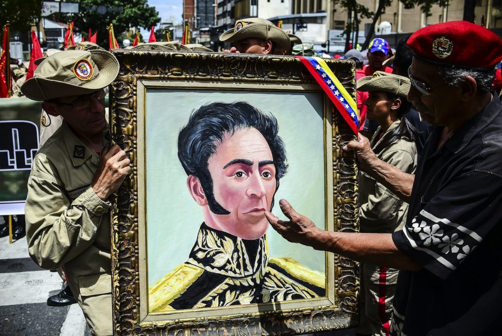 Militari dell’esercito venezuelano dimostrano il loro supporto al governo tenendo un ritratto del generale Bolìvar (AFP)