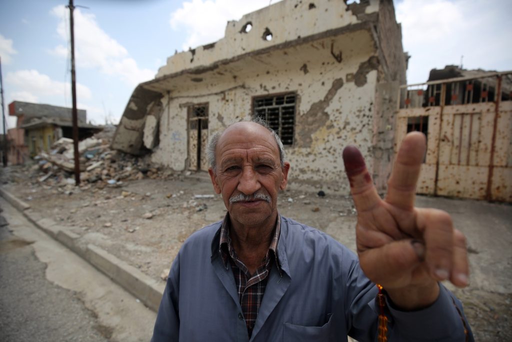 Un elettore iracheno di fronte alle macerie di Mosul (AFP)