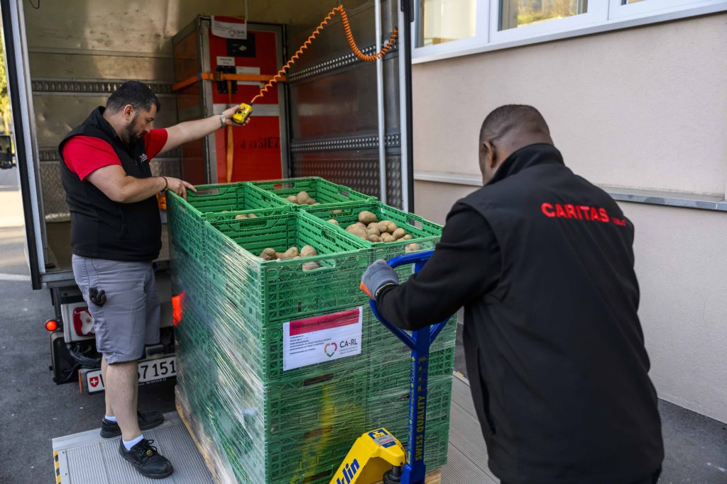 Collaboratori della Centrale alimentare di Caritas Vaud caricano derrate alimentari destinate ad associazioni attive sul territorio (Keystone)