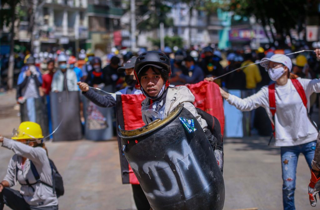 Un manifestante con uno scudo improvvisato nelle strade di Yangon (Shutterstock)