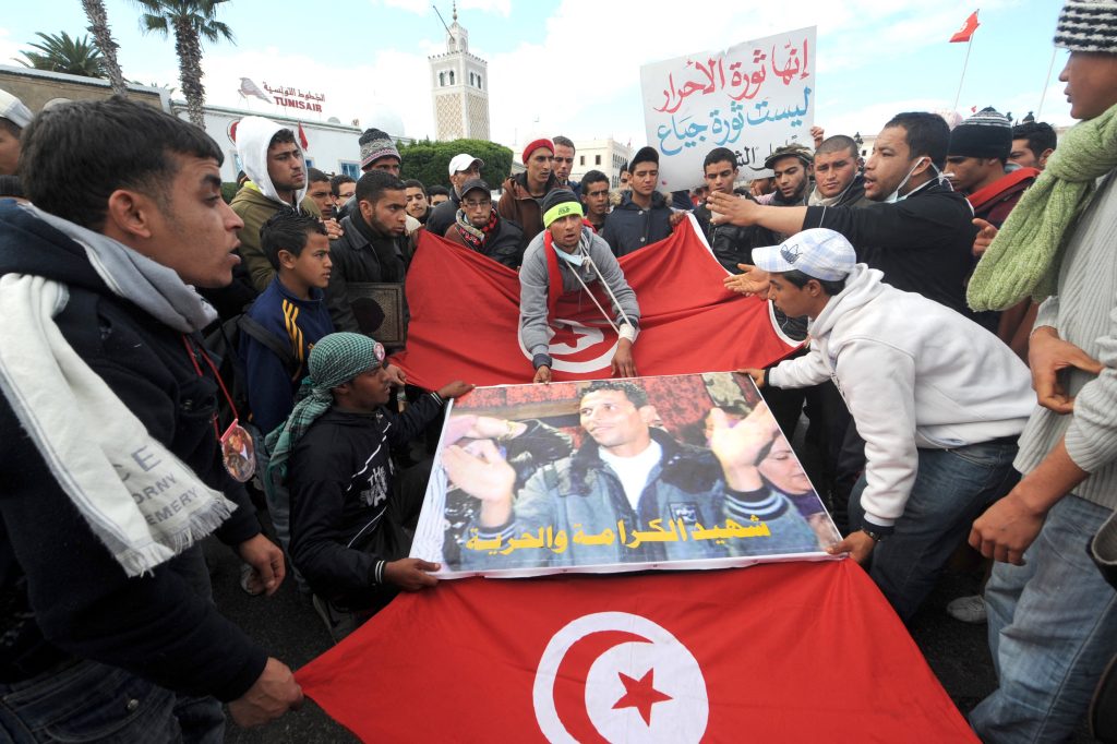 Un gruppo di manifestanti a Tunisi, nel gennaio 2011, con l’immagine di Mohamed Bouazizi che si diede fuoco in segno di protesta (AFP)