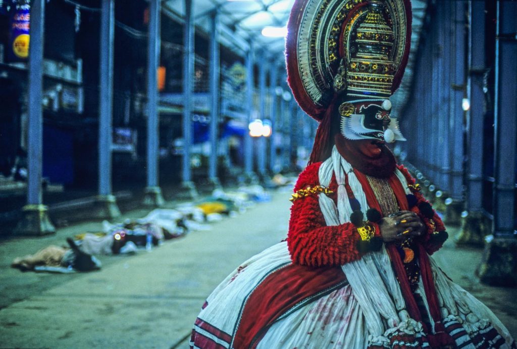 Attore prima della messa in scena al tempio Guruvayur; sullo fondo pellegrini addormentati