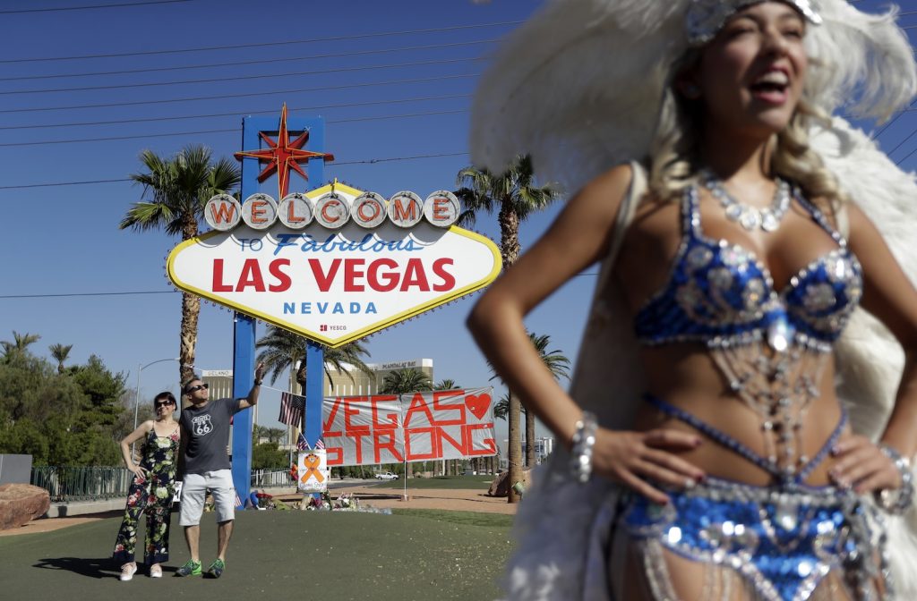 Due turisti si fanno fotografare davanti all'hotel Mandalay di Las Vegas da dove l'assassino ha provocato la strage (Keystone)