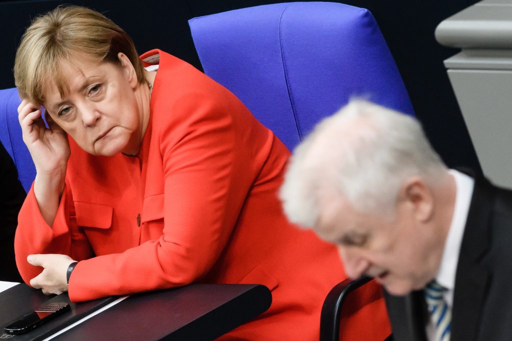 Una visibilmente affaticata Angela Merkel ascolta il suo ministro degli interni ed avversario Horst Seehofer (Keystone)