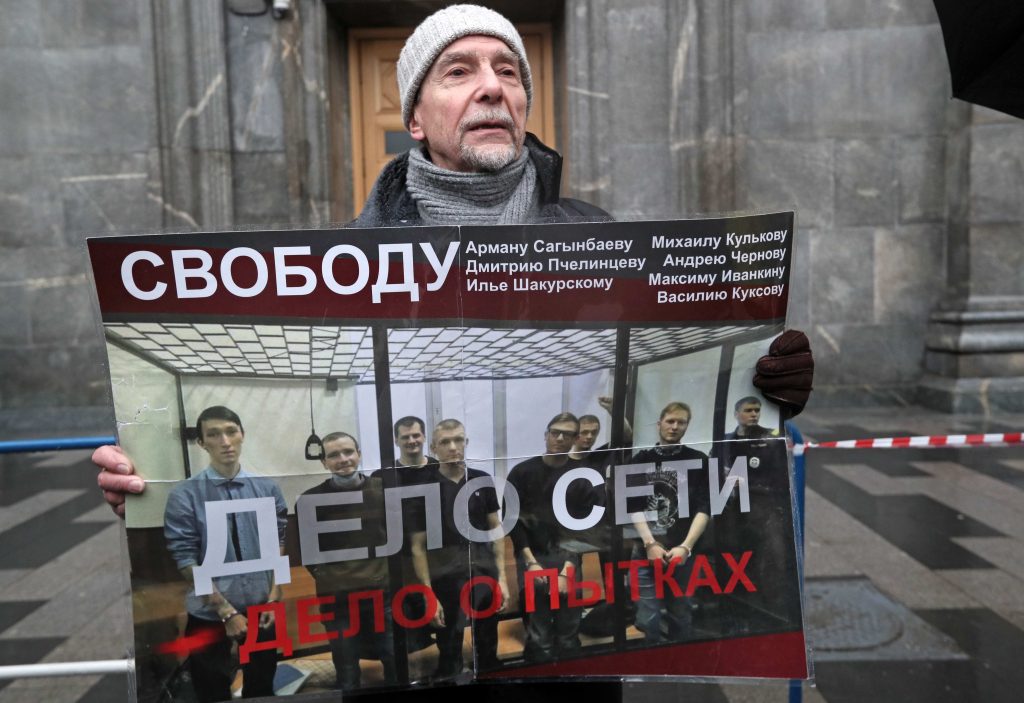 Un attivista manifesta davanti alla sede dell’ex KGB contro le torture e il processo a carico del gruppo di giovani (Keystone)